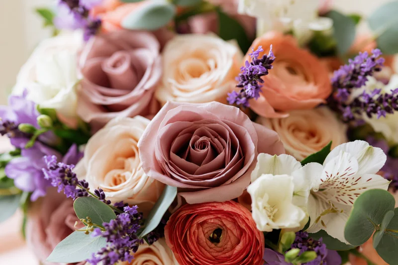 Close-up of a lush mixed bridal bouquet with dusty mauve roses, lavender, and greenery