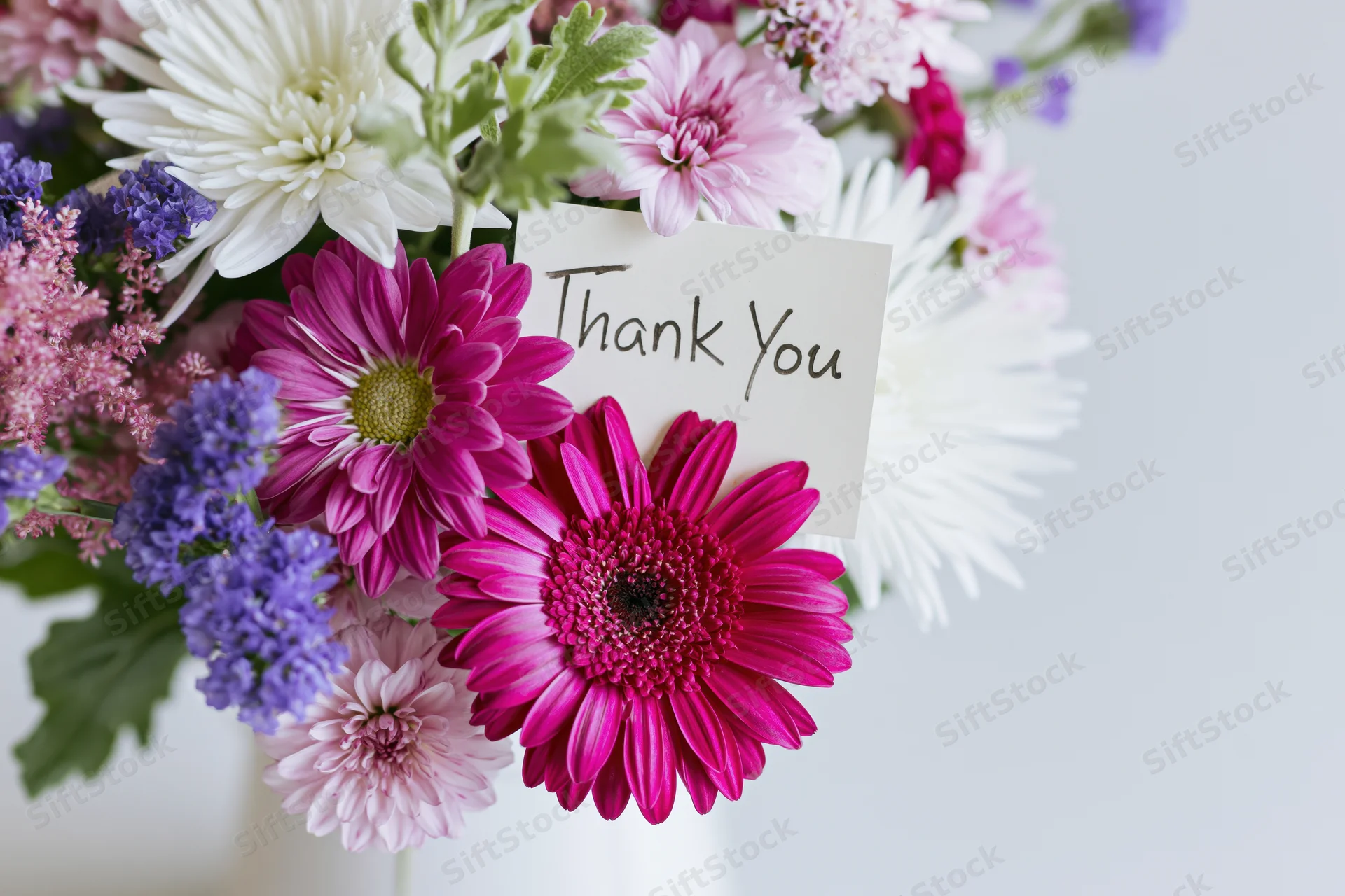 Mixed flower bouquet with handwritten thank you note tucked among blooms