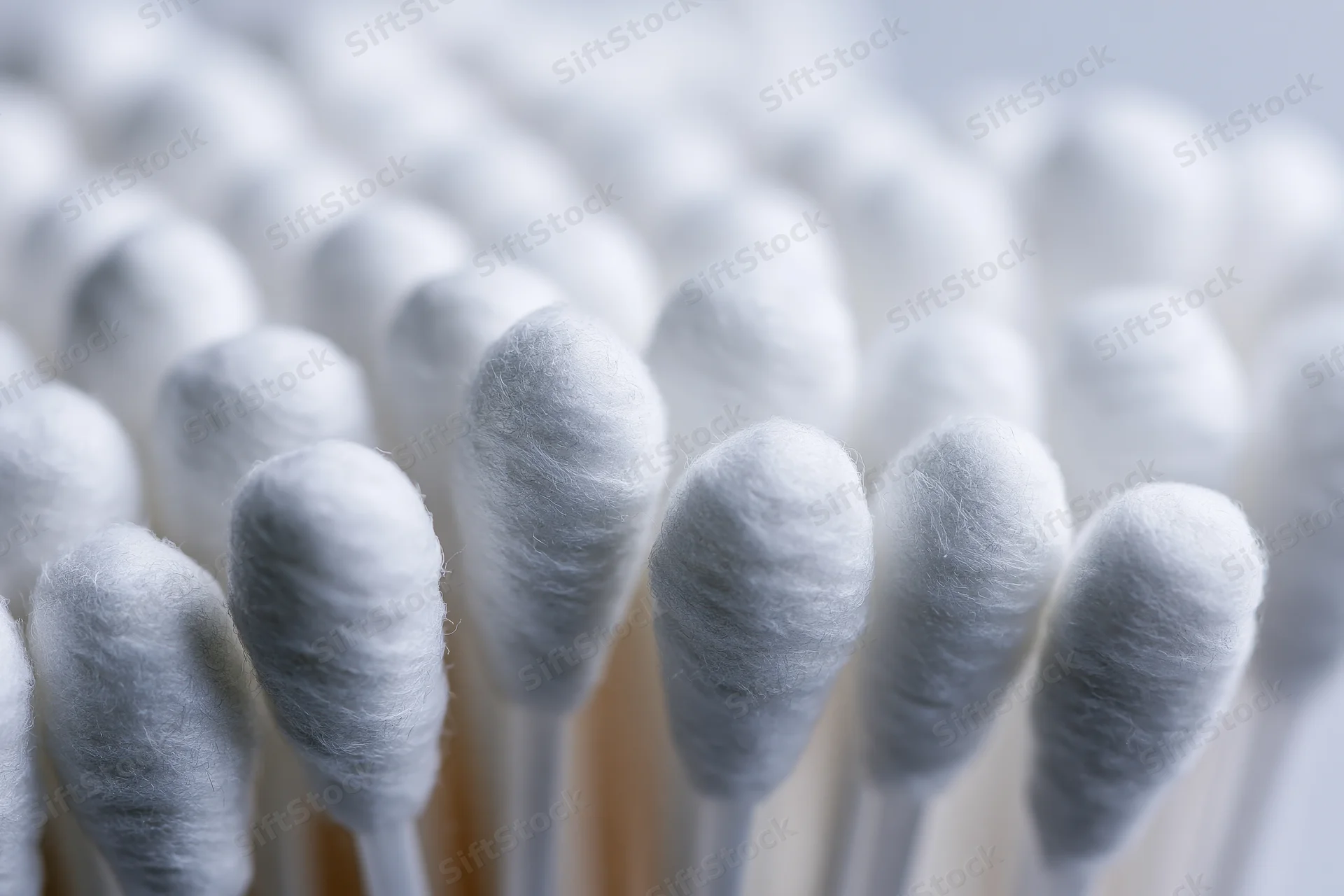 Close-up of white cotton swabs packed tightly together in rows
