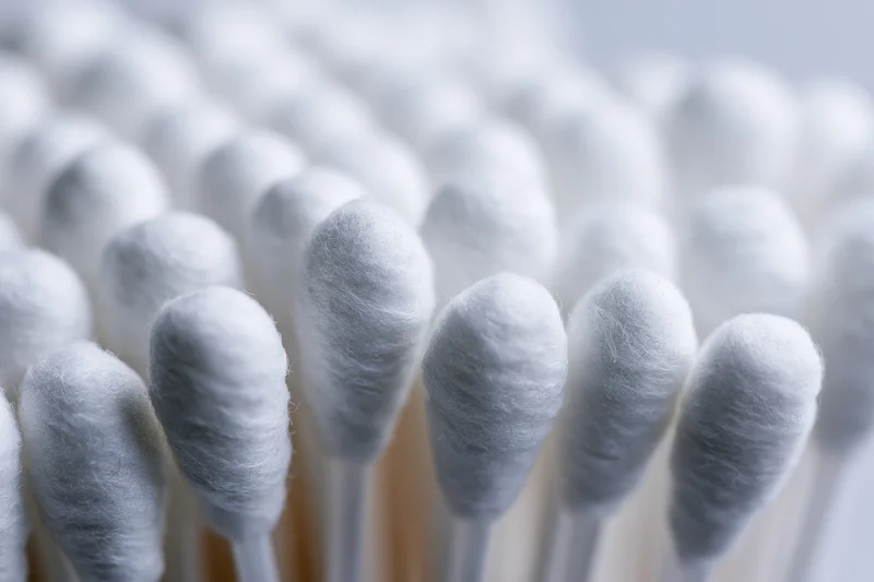 Close-up of white cotton swabs packed tightly together in rows