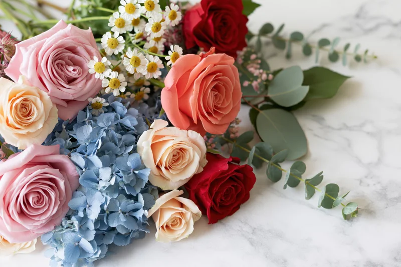 Mixed floral arrangement with roses, hydrangea, daisies and eucalyptus on marble surface