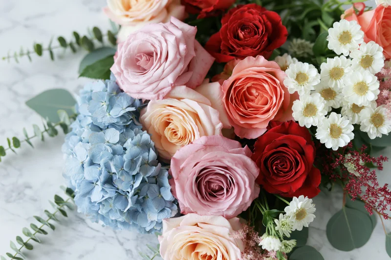 Mixed floral arrangement with roses, hydrangea and daisies on marble surface