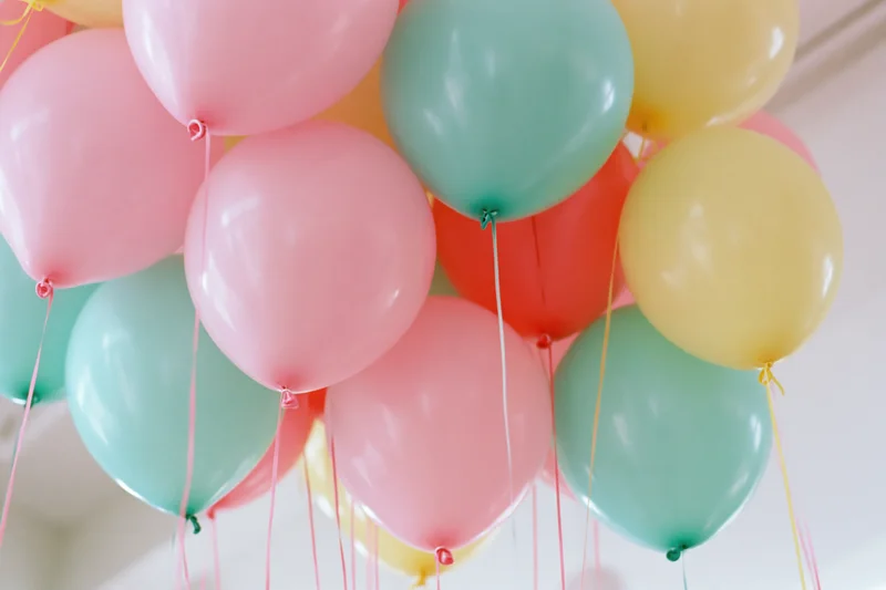 Cluster of colorful helium balloons floating indoors viewed from below