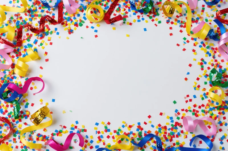 Colorful paper confetti and curled ribbon streamers scattered around a white center copyspace for party decoration