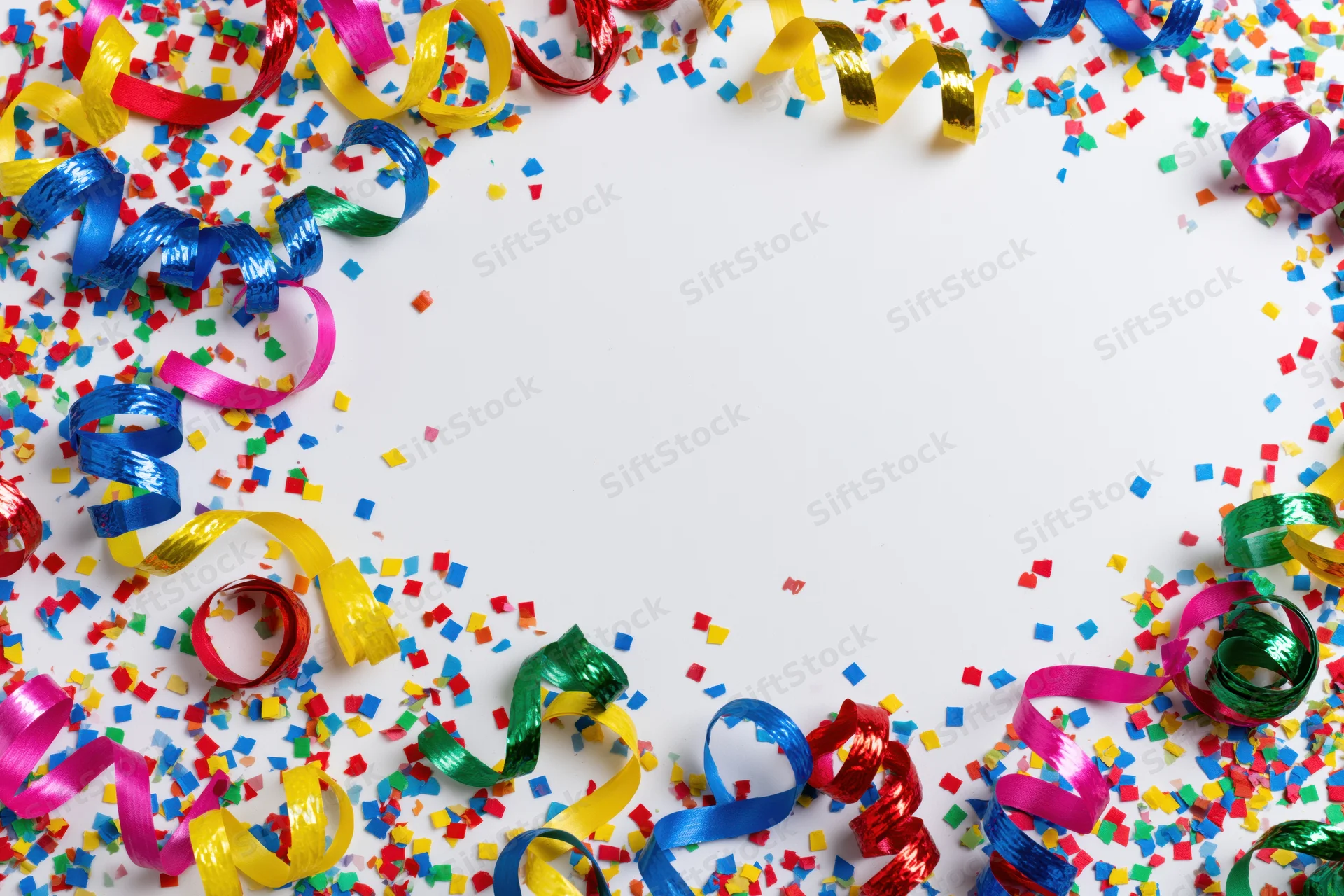 Colorful paper confetti and curled ribbon streamers scattered around a white background with copyspace