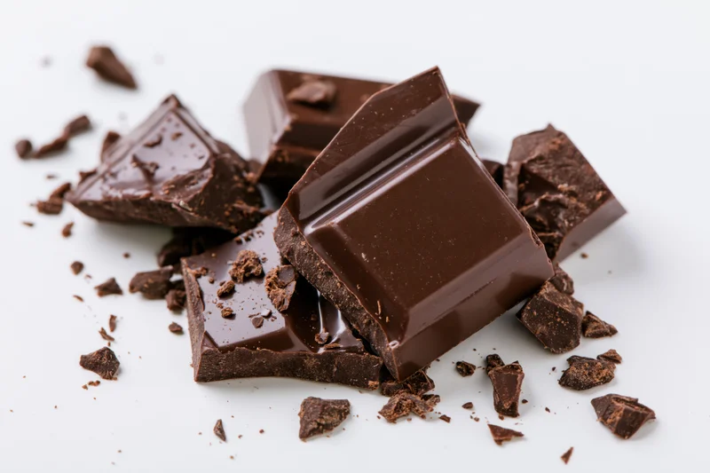 Broken dark milk chocolate bar pieces arranged on white background