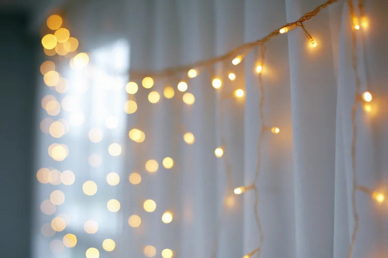 String lights draped over a white curtain creating a soft glowing ambiance indoors