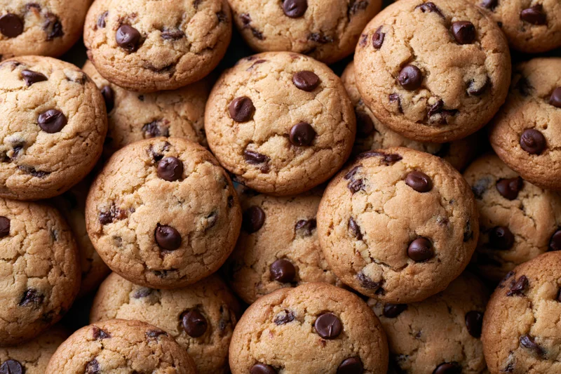 Closeup of dozens of freshly baked chocolate chip cookies arranged in a pile