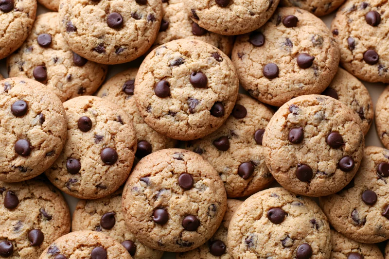 Closeup of freshly baked chocolate chip cookies piled together on a flat surface