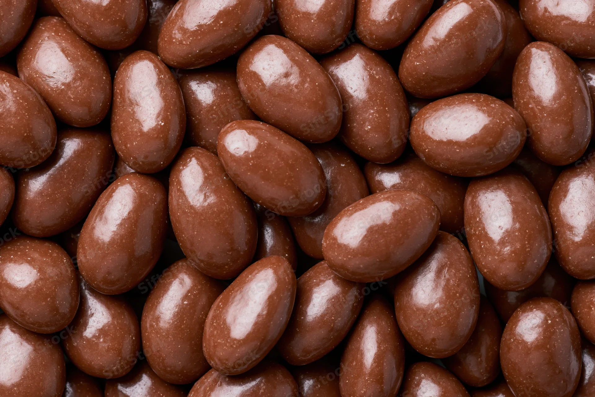 Closeup of glossy chocolate-covered almonds filling the frame