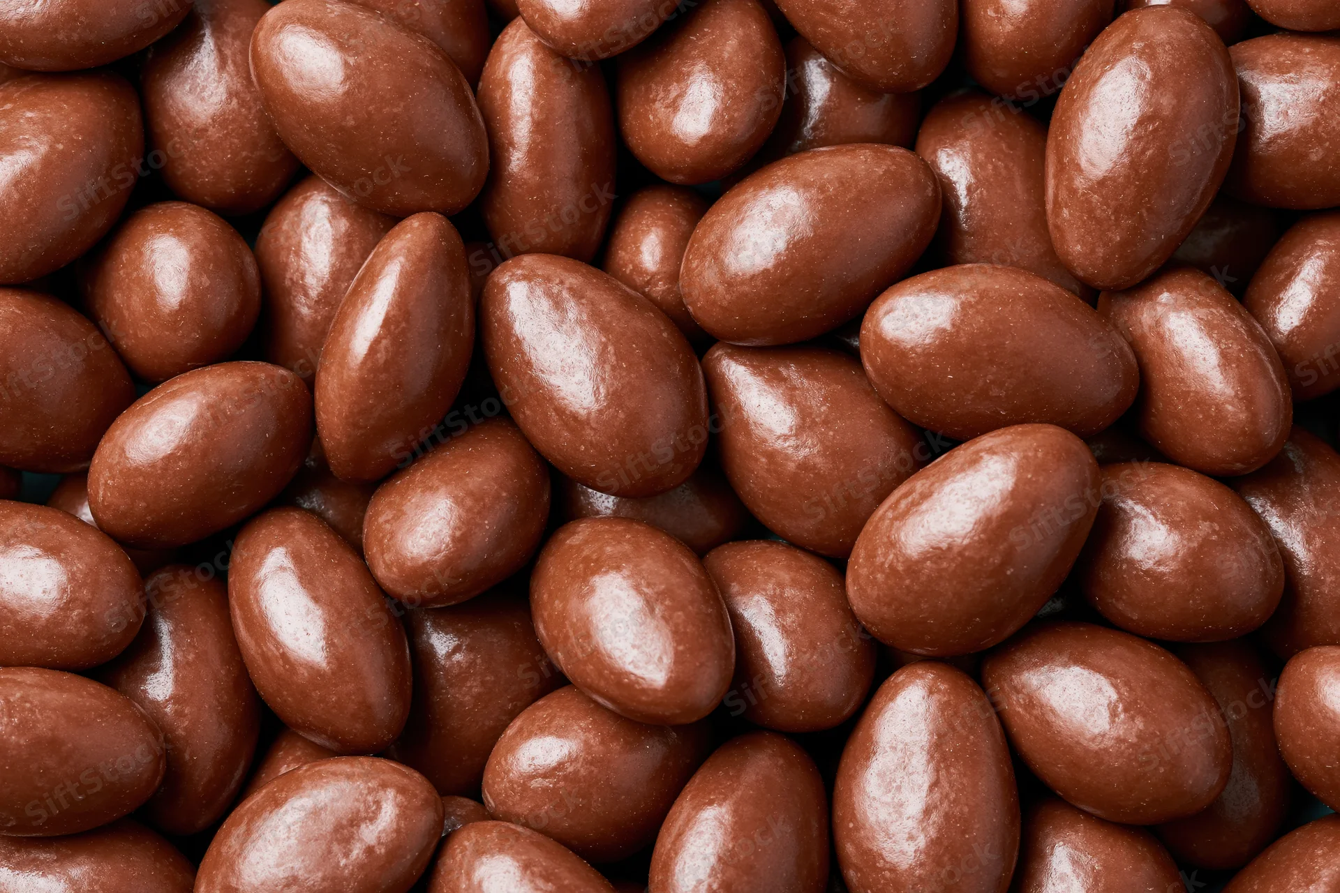 Glossy chocolate-covered almonds filling the frame in a close-up view