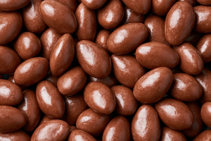 Glossy chocolate-covered almonds filling the frame in a close-up view