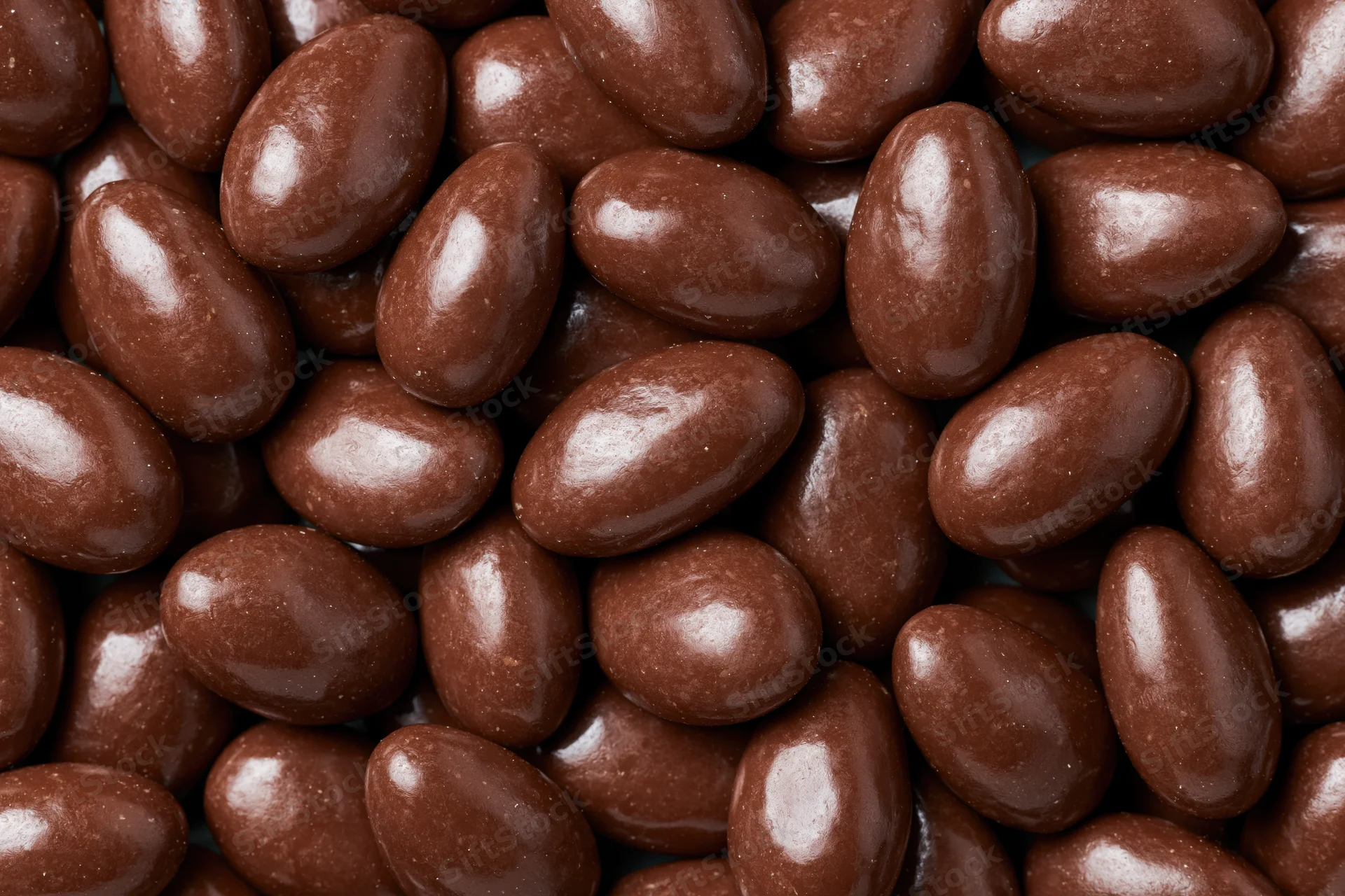 Glossy chocolate-covered almonds filling the frame in a close-up view