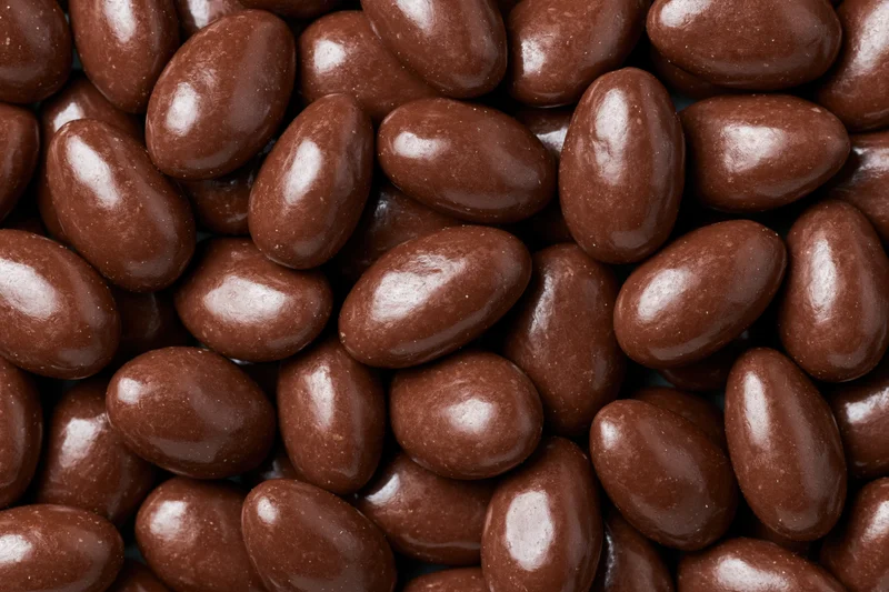 Glossy chocolate-covered almonds filling the frame in a close-up view