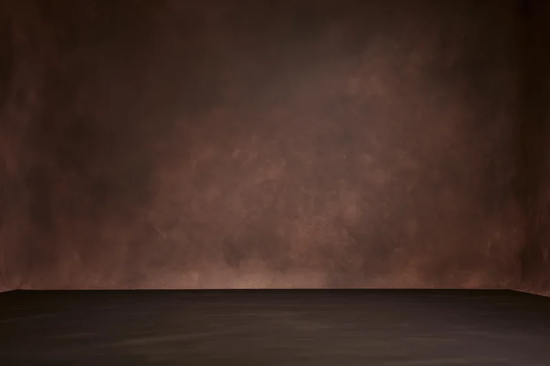 Empty studio backdrop with mottled dark brown painted wall and dark floor