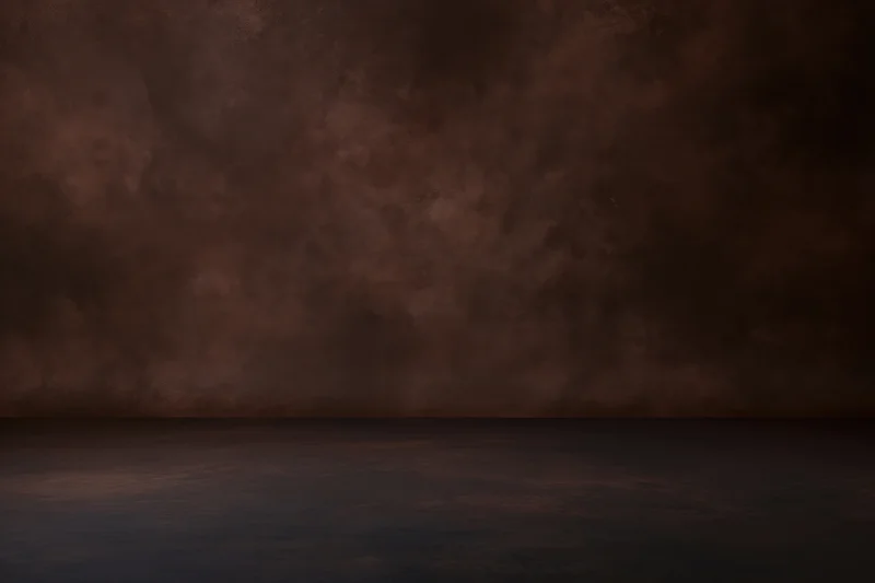 Empty studio space with mottled dark brown painted backdrop and floor