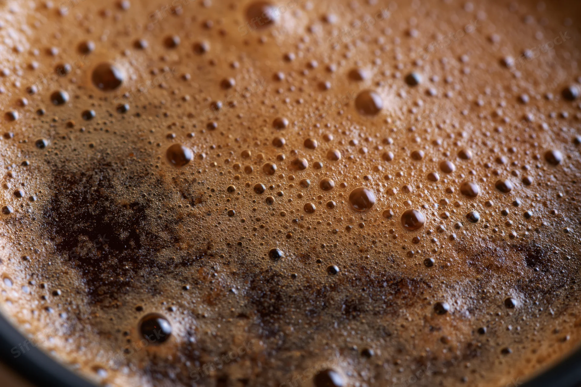 Close-up of freshly brewed black coffee with crema and bubbles on surface
