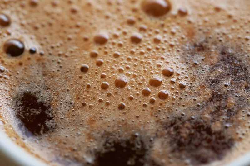 Extreme close-up of coffee crema with bubbles and foam in a white cup