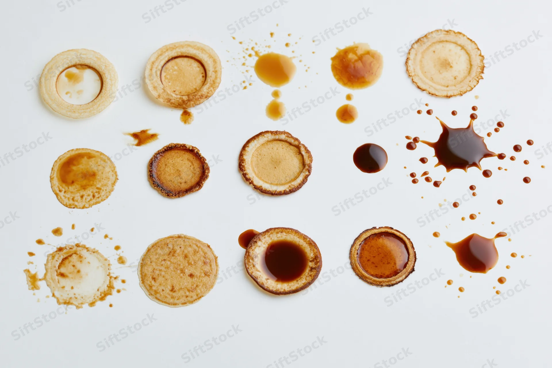 Coffee stains and splatter marks arranged in rows on a white surface