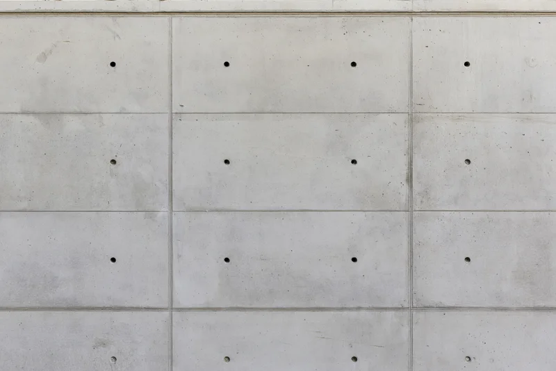Gray concrete wall surface with grid pattern and small holes, exterior building facade