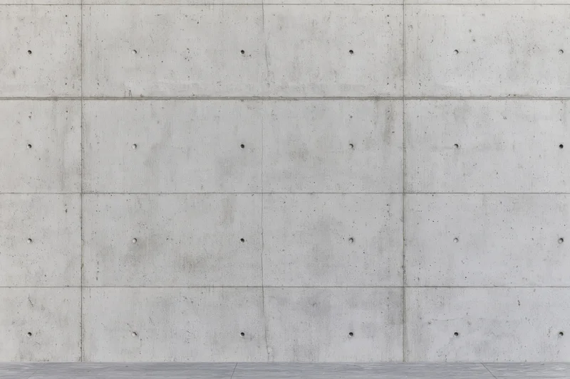 Flat concrete wall surface with grid pattern and small holes, exterior building facade