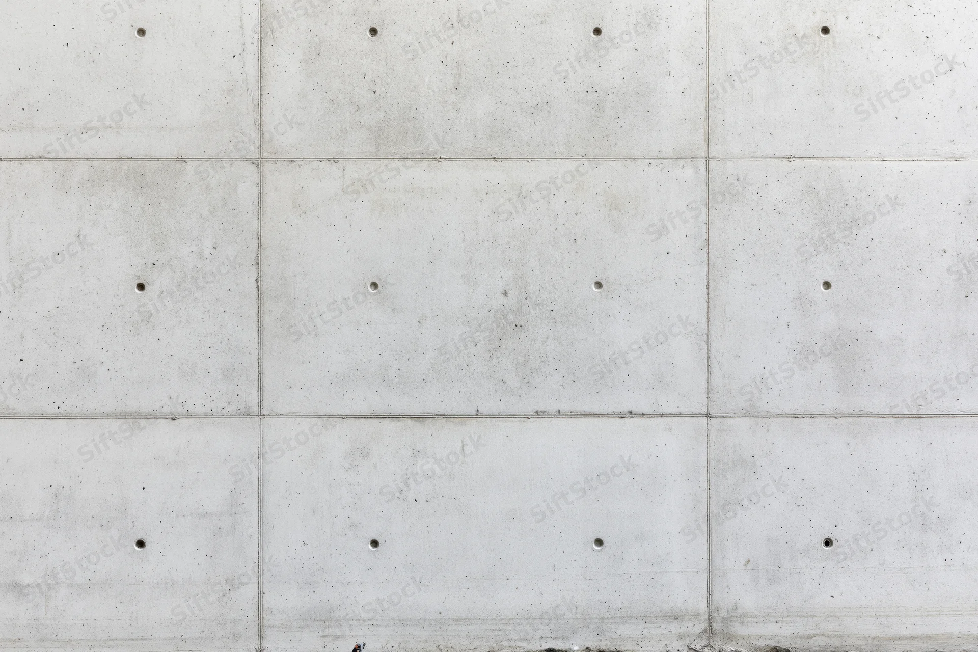 Flat concrete wall surface with grid pattern and bolt holes