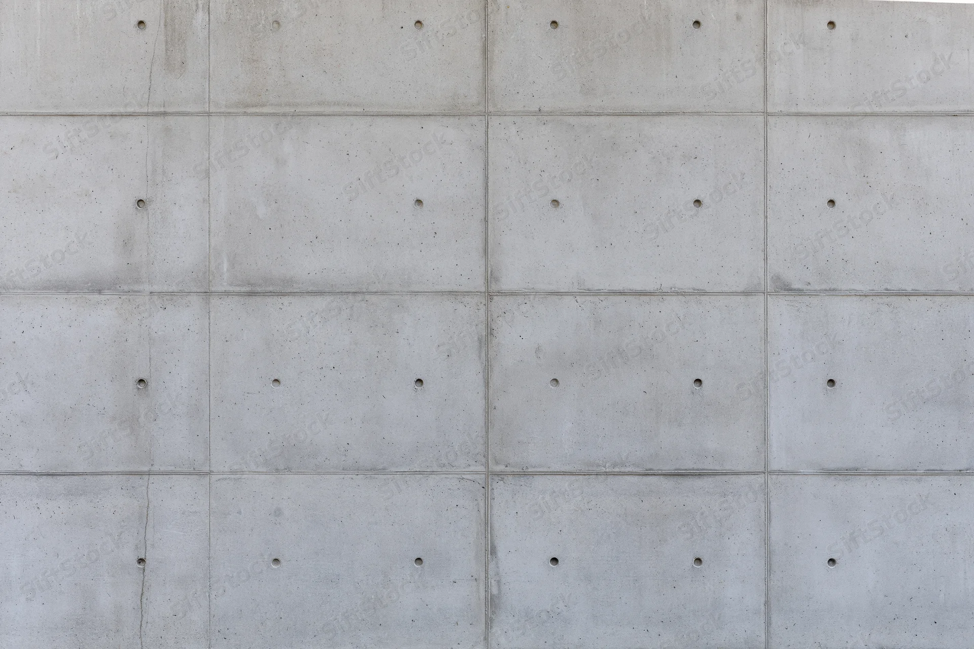 Flat concrete wall surface with grid pattern and small holes, exterior building facade