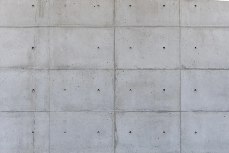 Flat concrete wall surface with grid pattern and small holes, exterior building facade