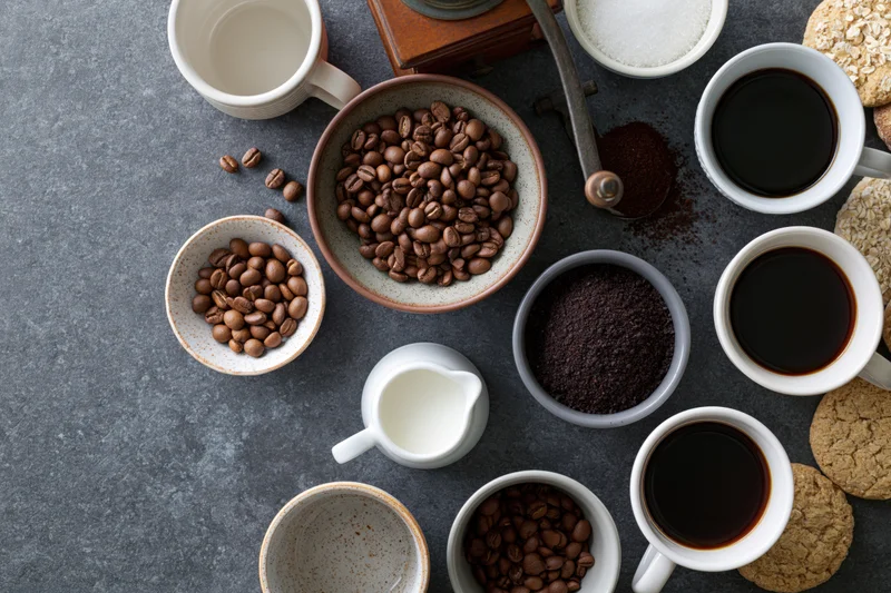 Coffee beans and brewing ingredients arranged on a gray stone surface in a flat lay overhead composition