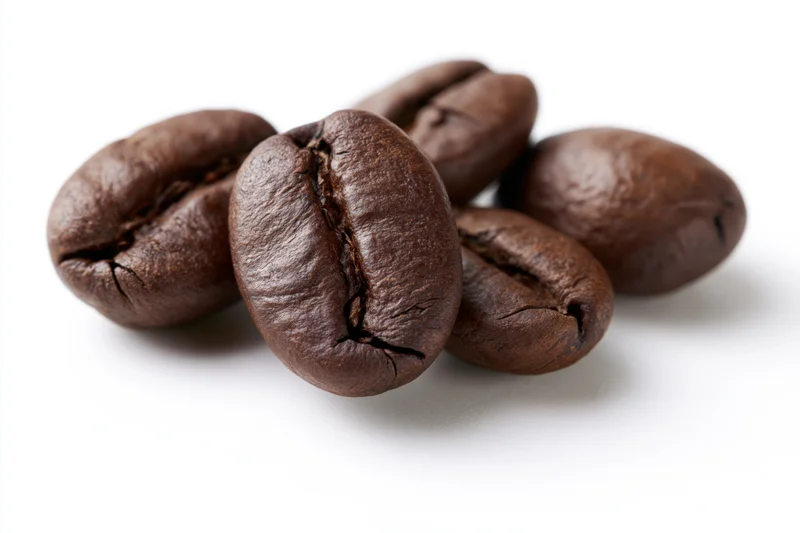 Dark roasted coffee beans arranged loosely on white background
