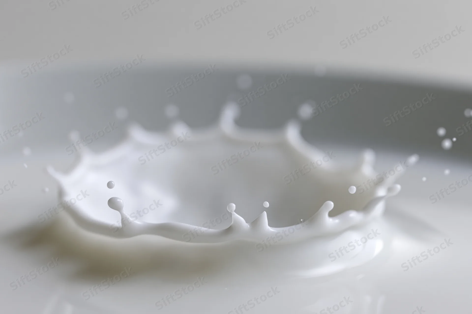 Milk splash frozen mid-motion forming a crown shape on a smooth white surface