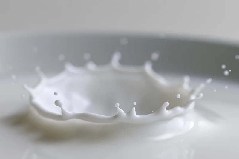 Milk splash frozen mid-motion forming a crown shape on a smooth white surface