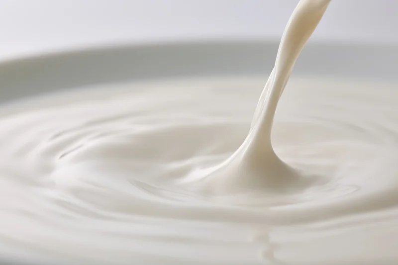 Milk pouring in a smooth stream onto a pooling surface