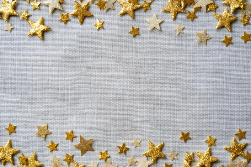 Gold metallic star confetti arranged along top and bottom edges of gray fabric background with central copyspace