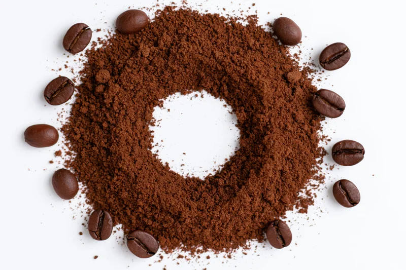 Ground coffee arranged in a circular ring with whole beans on white background