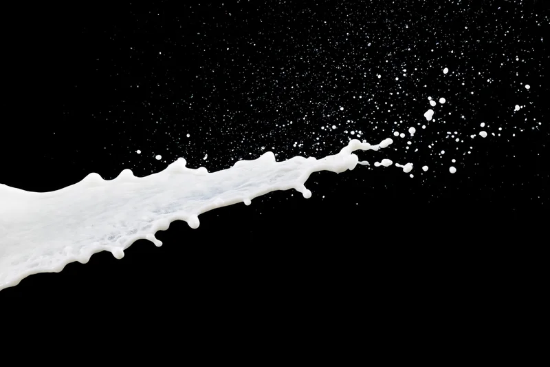 White milk splash in mid-air diagonal against black background