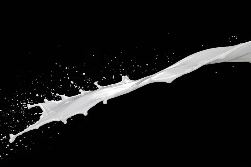 Diagonal milk splash mid-air against black background