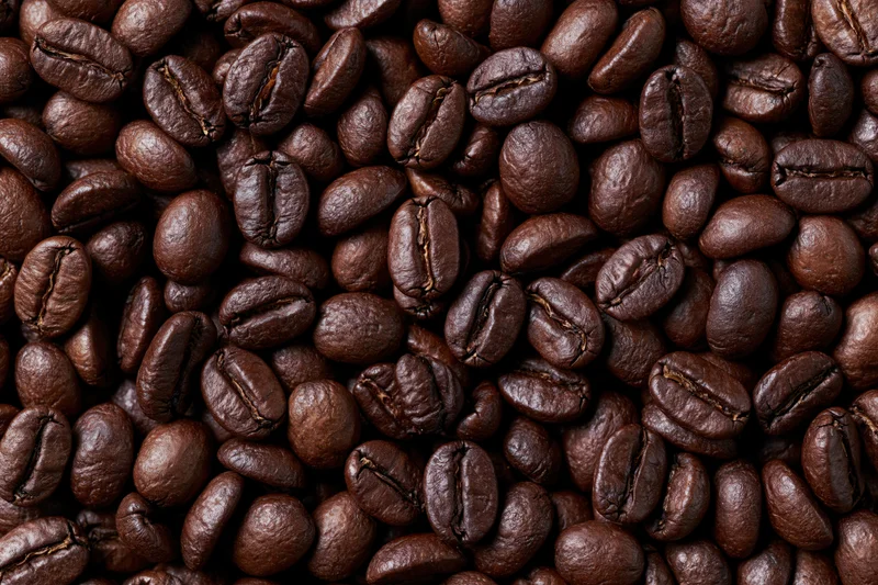 Hundreds of dark roasted coffee beans filling the entire frame