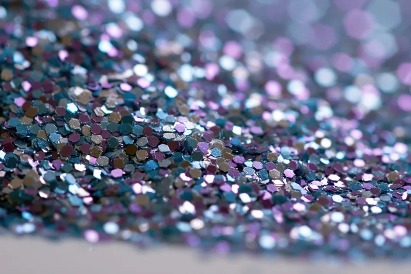 Macro closeup of loose holographic glitter scattered densely on a surface