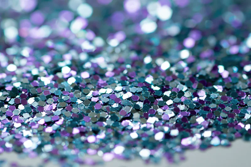 Macro closeup of loose holographic glitter scattered densely on a surface
