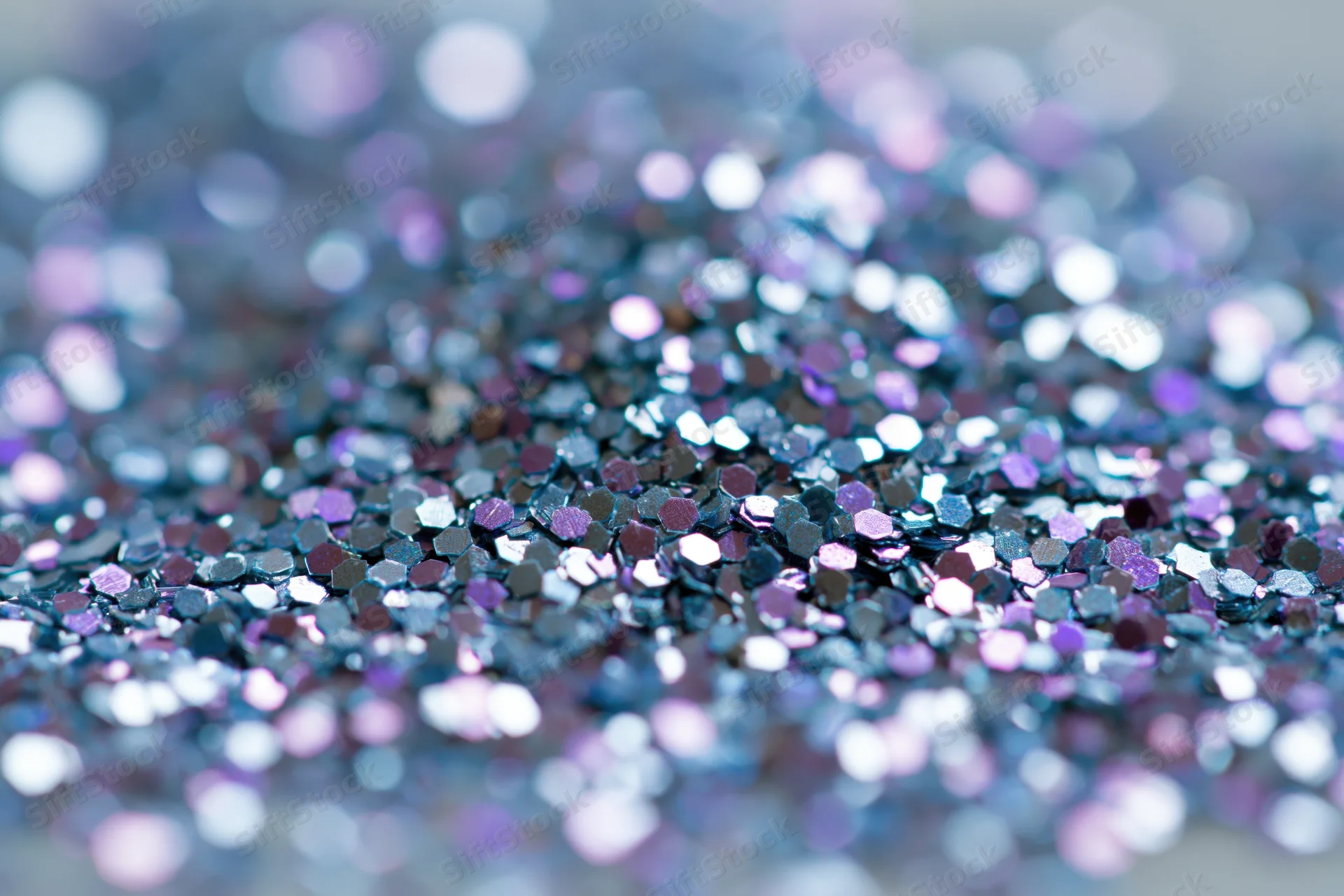 Macro closeup of loose holographic glitter scattered densely on a surface