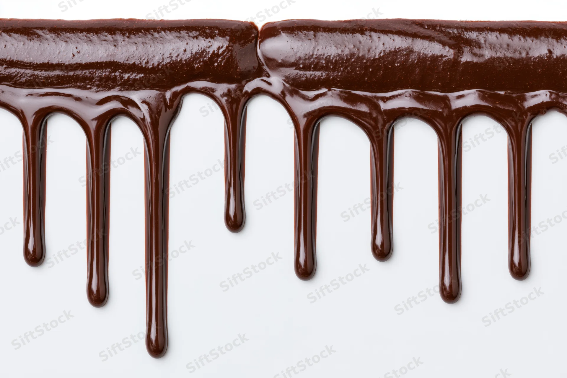 Melted dark chocolate dripping in glossy streams against a white background