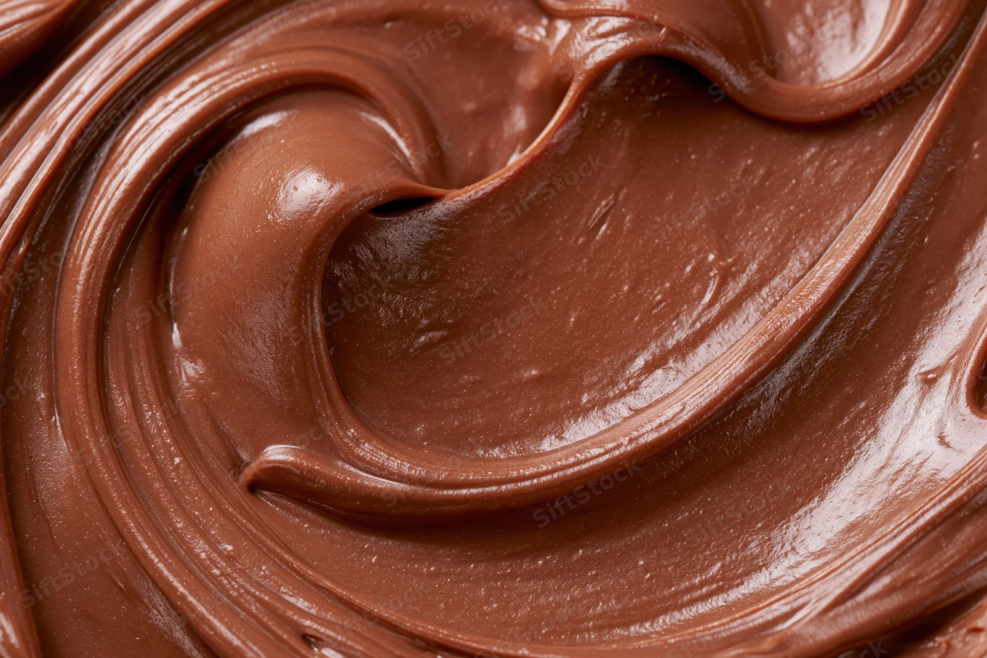 Melted milk chocolate spread in swirling patterns across a flat surface