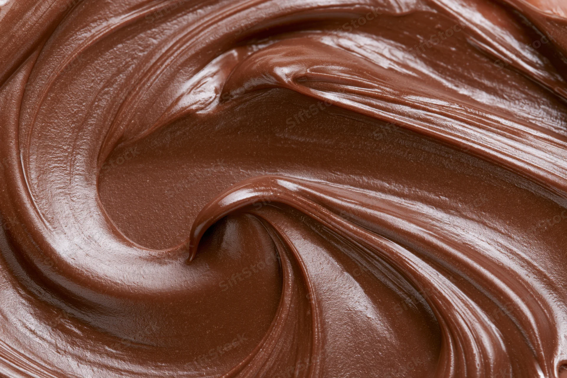 Melted milk chocolate spread in swirling patterns across a flat surface