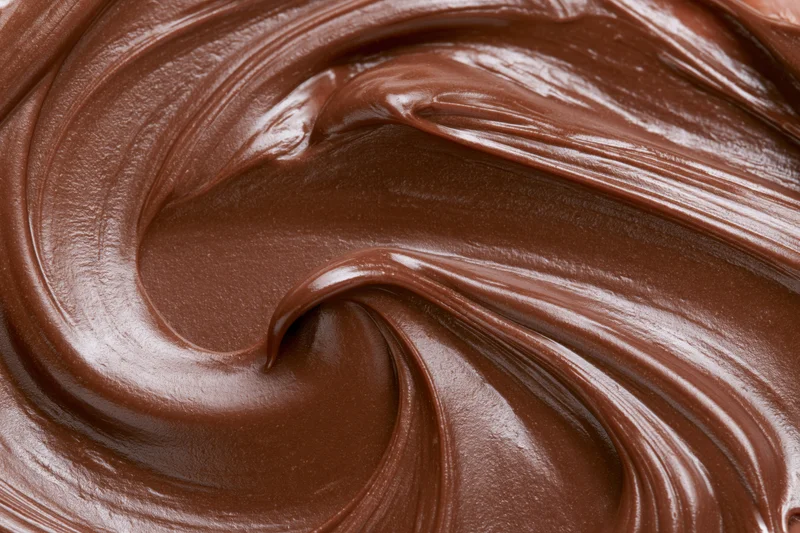 Melted milk chocolate spread in swirling patterns across a flat surface