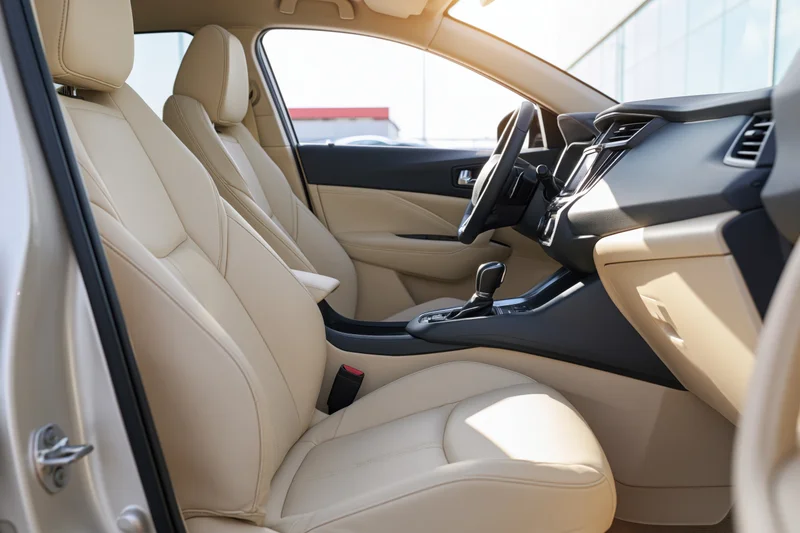 Interior of a modern compact SUV viewed from the passenger side door showing beige leather seats and dashboard