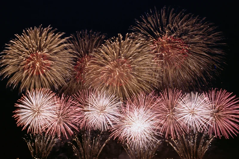 Fireworks bursting simultaneously across the night sky during a celebration