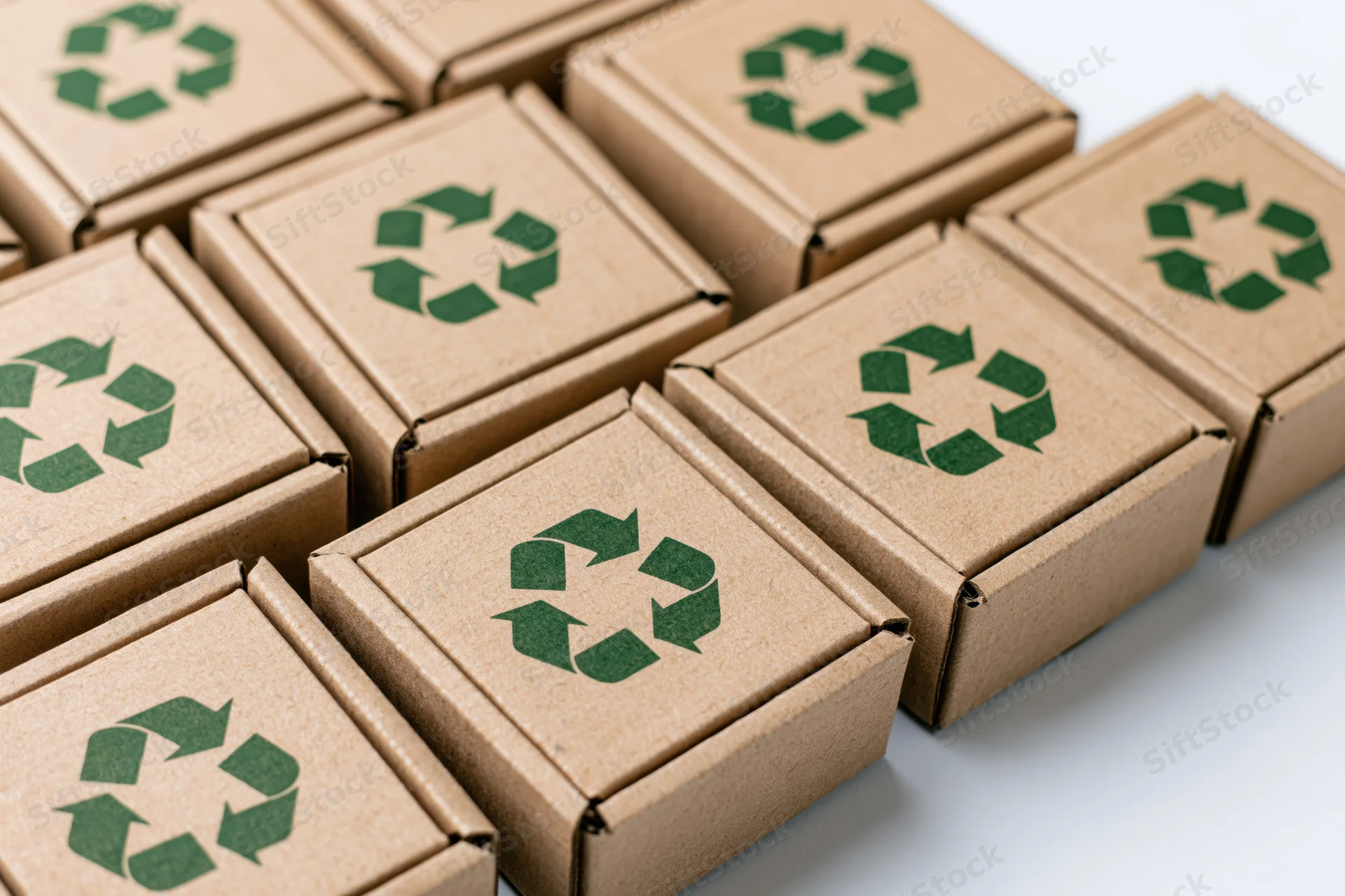 Multiple flat corrugated cardboard mailer boxes arranged in a grid with green recycling symbols on white surface