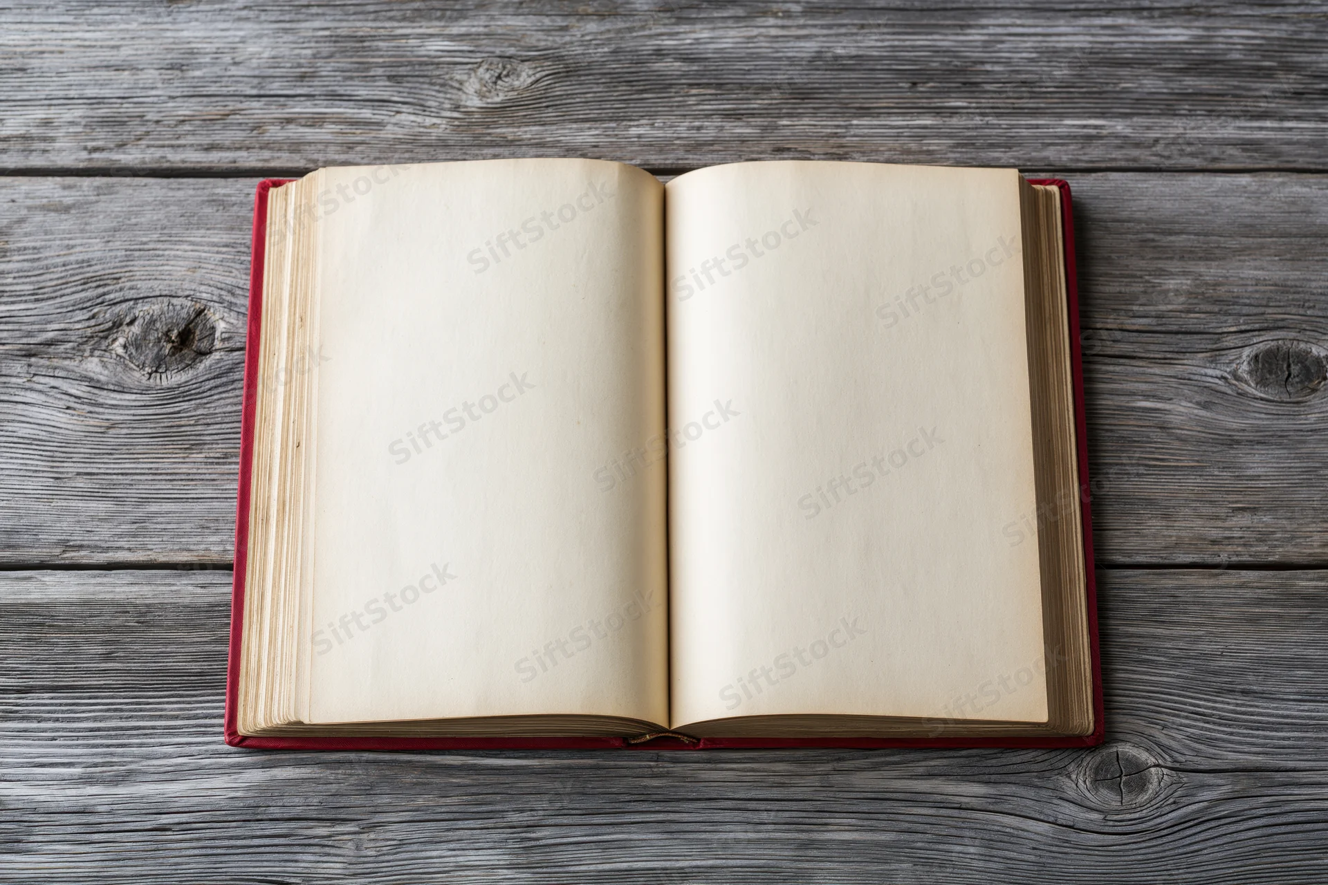 Open hardcover book with blank cream pages lying flat on weathered gray wooden surface