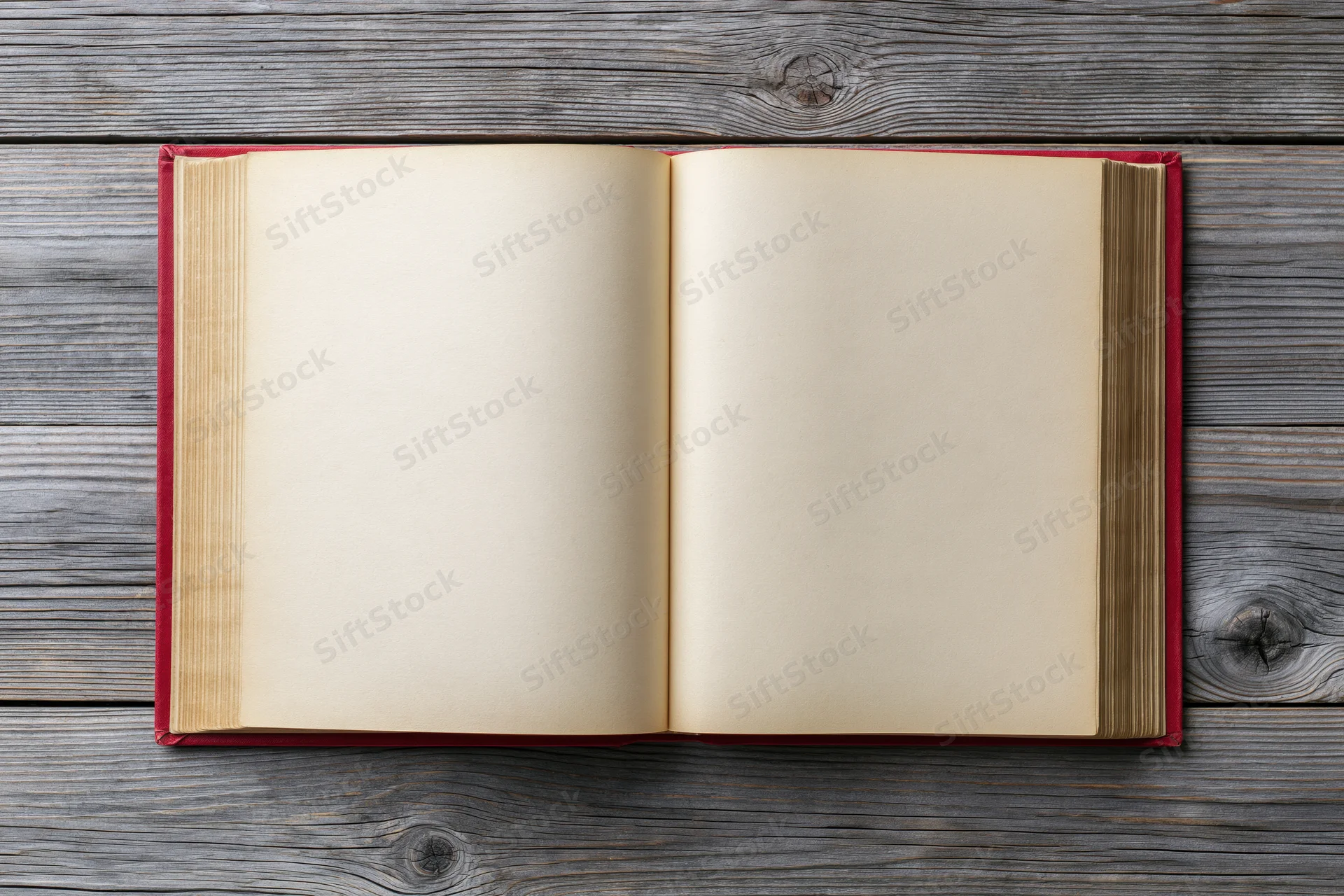 Open hardcover book with blank pages lying flat on weathered wooden surface